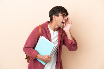 Young student caucasian man isolated on ocher background shouting with mouth wide open to the side