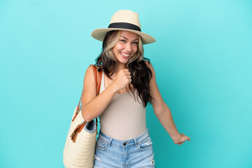 Fototapeta premium Teenager Russian girl with pamel and beach bag isolated on blue background celebrating a victory