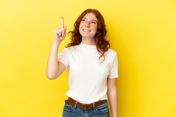 Teenager reddish woman isolated on yellow background intending to realizes the solution while lifting a finger up