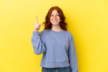 Teenager reddish woman isolated on yellow background pointing up a great idea