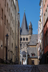 Low angle view on narrow lane in old town Cologne and background tower of Great St. Martin Church in Köln, Germany. 