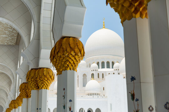 exterior of Sheikh Zayed Grand Mosque seen between pillars of path in abu dhabi, united arab emirates