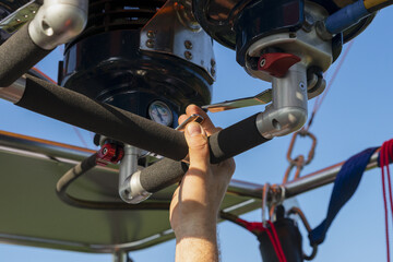 Closeup of a person fixing the hot air balloon burner under the sunlight and a blue sky