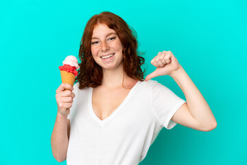 Teenager reddish woman with a cornet ice cream isolated on blue background proud and self-satisfied