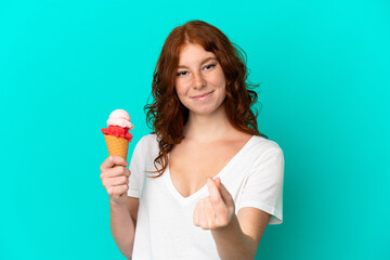 Teenager reddish woman with a cornet ice cream isolated on blue background making money gesture