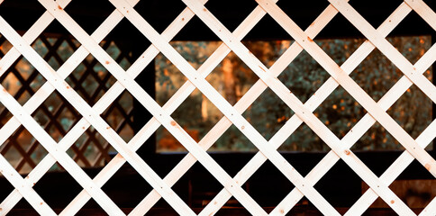 The lattice is wooden, diagonal, diamond-shaped. Close-up