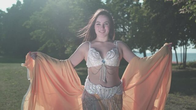 A beautiful girl in an oriental yellow dress dancing a belly dance on the coast of the sea. 50fps