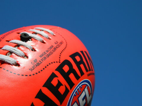 Close up of an AFL football on a blue sky background