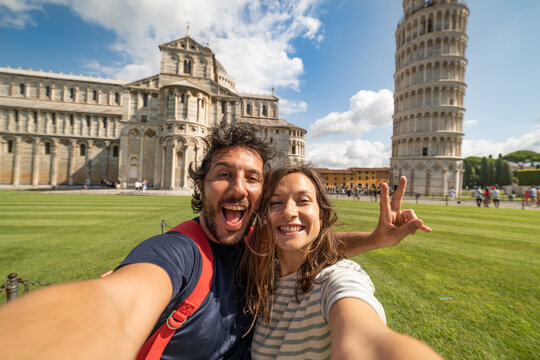 Travel tourists friends taking photo selfi with smartphone in Pisa, Tuscany. happy couple in love traveling in Europe having fun taking self-portrait picture in Pisa by Leaning Tower of Pisa, Italy.