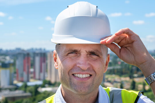 Portrait of smiling construction engineer in hardhat and with jacket on shoulders. High quality photo