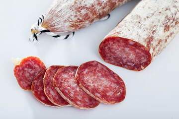 Image of spanish longaniza salami sausages cut in slices on a white surface, close-up