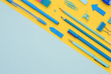 Office stationery on a two-tone background with space for text. The blue stationery on yellow are set diagonally against the yellow part of the background. Flat lay with copy space.