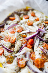 vegan homemade focaccia bread with cherry tomatoes and onions before being cooked, healthy plant-based food
