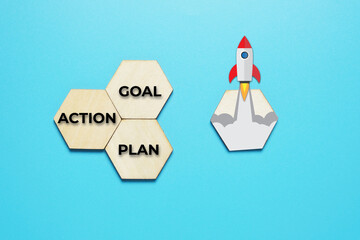 A picture of hexagon wooden written GOAL, up arrow and rocket blast. Goal achievement concept