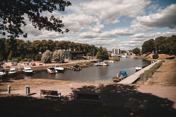 Fototapeta na wymiar Parnu, Estonia / July 30, 2021: Boats and people walking in a park by the Valli lake in Parnu, beautiful colorful estonian city by the Baltic sea, Europe