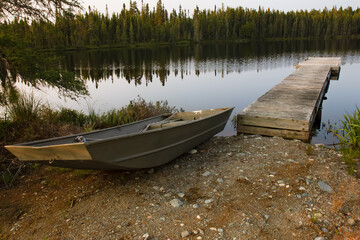 dock in lake water near forest with fishing boat in summer