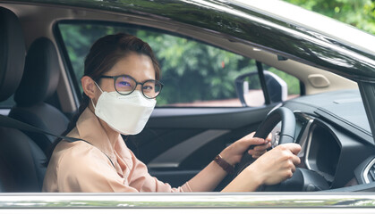 Happiness Asian woman wearing surgical mask while driving car. During covid-19 pandemic be sure to bring a mask with you when you leave home.