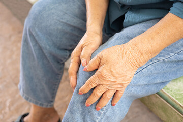 Close up shot of sitting seniors knees with hands touching or grabbing due to feeling pain and hurt shows elderly disease due to muscle weakness and joint ache which is health care problem.