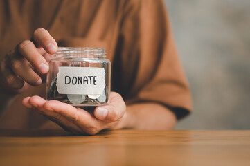 Man holding money jar with DONATE word written text label for giving and donation concept, saving, fundraising charity, Coronavirus economic stimulus rescue package