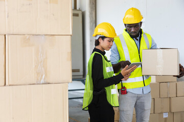 African American and Asian workers wearing safety vest while working in warehouse checking and tracking for the inventory