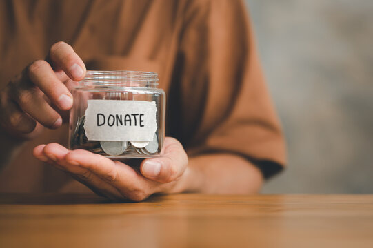 Man holding money jar with DONATE word written text label for giving and donation concept, saving, fundraising charity, Coronavirus economic stimulus rescue package