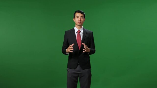 Young Asian Businessman In Suit Jacket Standing And Presenting Something On Green Screen Background
