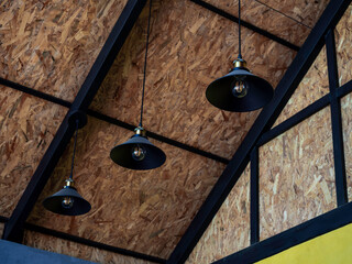 Three black retro style round hanging ceiling lights decoration under the wooden roof construction.