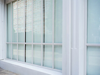 Modern white clean building with tall glass window wall with blinds, outdoors. 