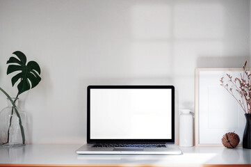 Mockup creative workspace with blank screen laptop computer and supplies on wooden table.