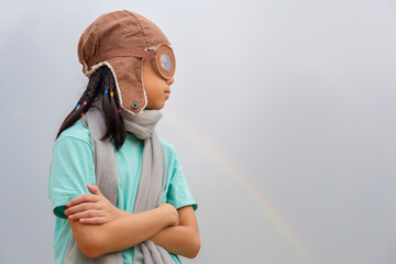 Portrait of Asian child girl in the old style pilot uniform stands with arms crossed, Happy kid playing outdoors