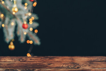 Empty wooden table in front of decorated christmas tree branch.