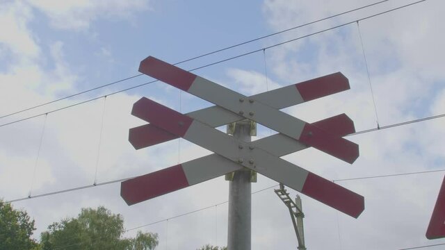 Low angle dolly of red white railroad crossing sign indicating multiple tracks at level crossing
