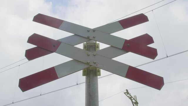 imposing low angle view of red white railroad crossing sign indicating multiple tracks at level crossing