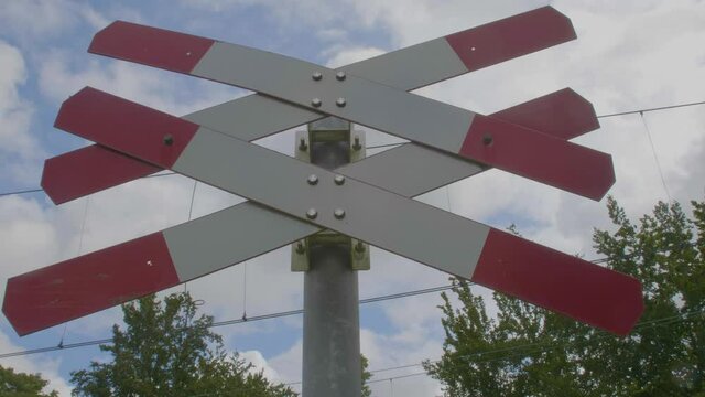 close low angle view of red white railroad crossing sign indicating multiple tracks at level crossing