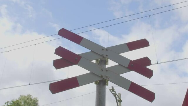 tilt up to red white railroad crossing sign indicating multiple tracks at level crossing