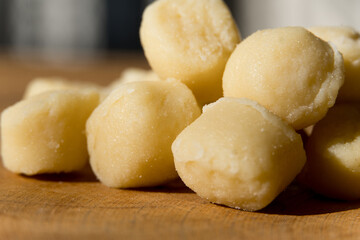 Gnocchi pasta pre-cooked on a wooden board with grated cheese and basil. Macro close up. Selective focus.