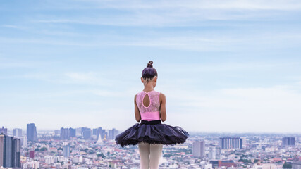 ballerina girl in ballet dress standing on building rooftop