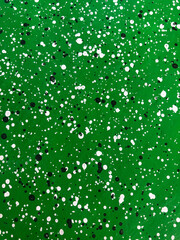 Vertical green cement wall decorated with black and white dots pattern style.