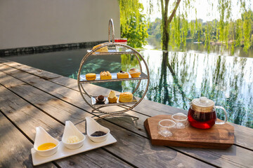 Afternoon tea set with dessert on wooden floor beside swimming pool