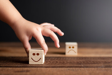 Child hand holding wooden cube with smiling face icon. Concept of Emotion,expression and rating