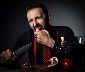 Adult bearded man in black shirt, striped tie and suspenders sits at table served with bottle and...
