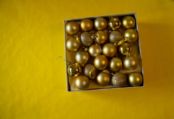 yellow background, a box with yellow Christmas balls for the Christmas tree