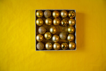 yellow background, a box with yellow Christmas balls for the Christmas tree