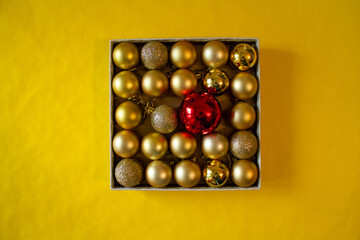 yellow background, a box with yellow Christmas balls and red ball for the Christmas tree