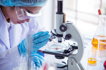 Closeup Woman scientist hand use dropper in lab look at science microscope medical test, research biology chemistry. Females technician laboratory analyzing blood scientific pharmaceutical research.