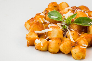 Gnocchi with juice sauce with grated cheese and basil served on the plate. Close-up. Selective focus.