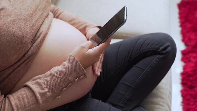 a young pregnant latin woman using a phone