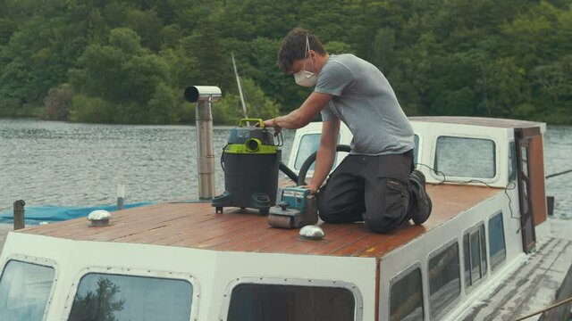 Young man begins taslk of removing varnish from wood boat forecabin