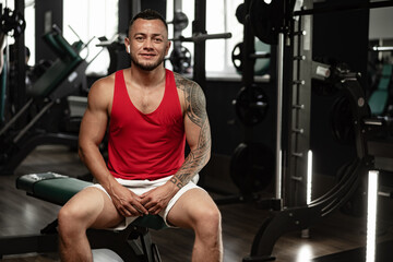 Fototapeta na wymiar Portrait of man bodybuilder in red shirt in gym