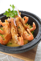 deep fried crispy big fresh tiger prawn in spicy chilli curry sauce in hot clay pot in white background asian halal menu